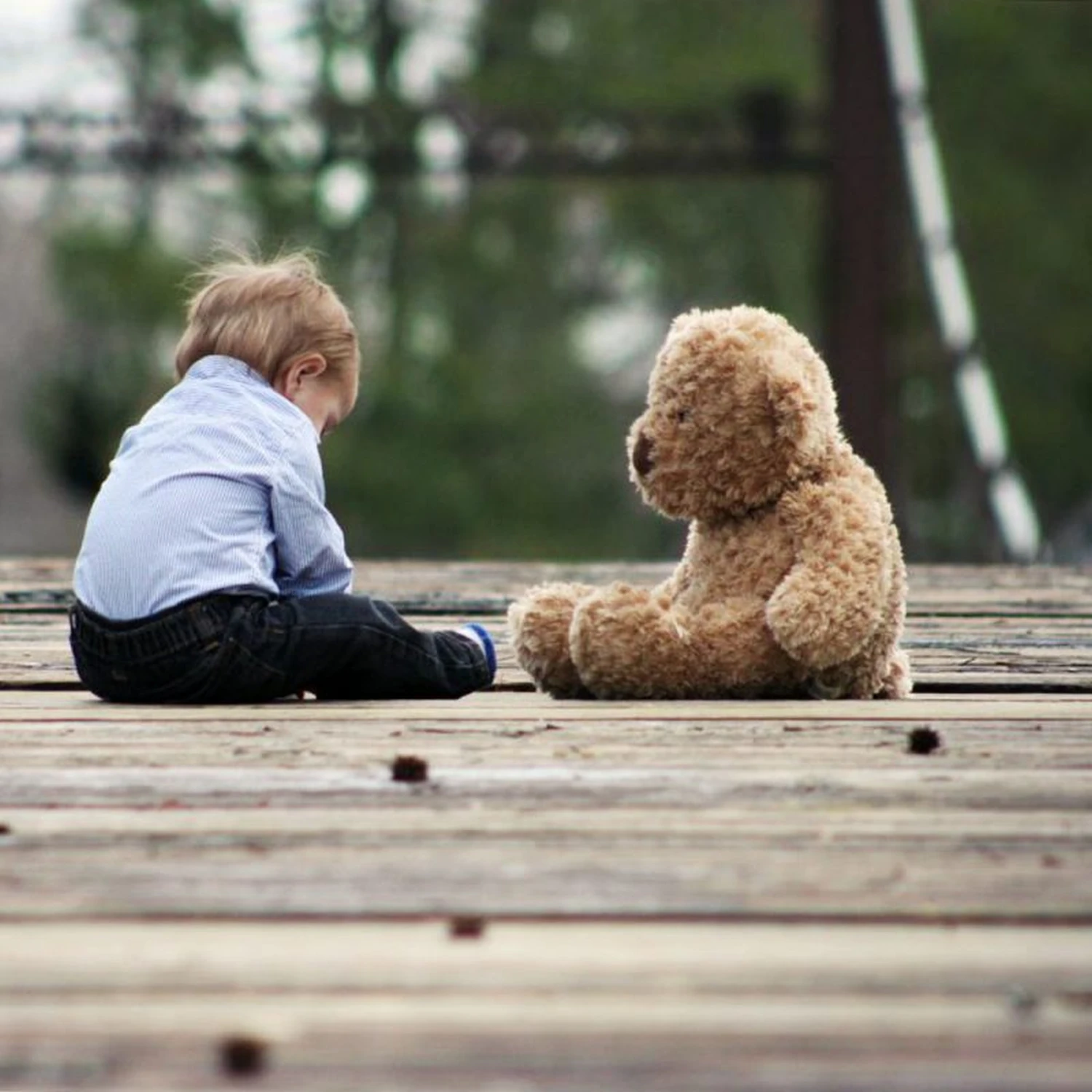 Ein Junge und ein Teddybär sitzen