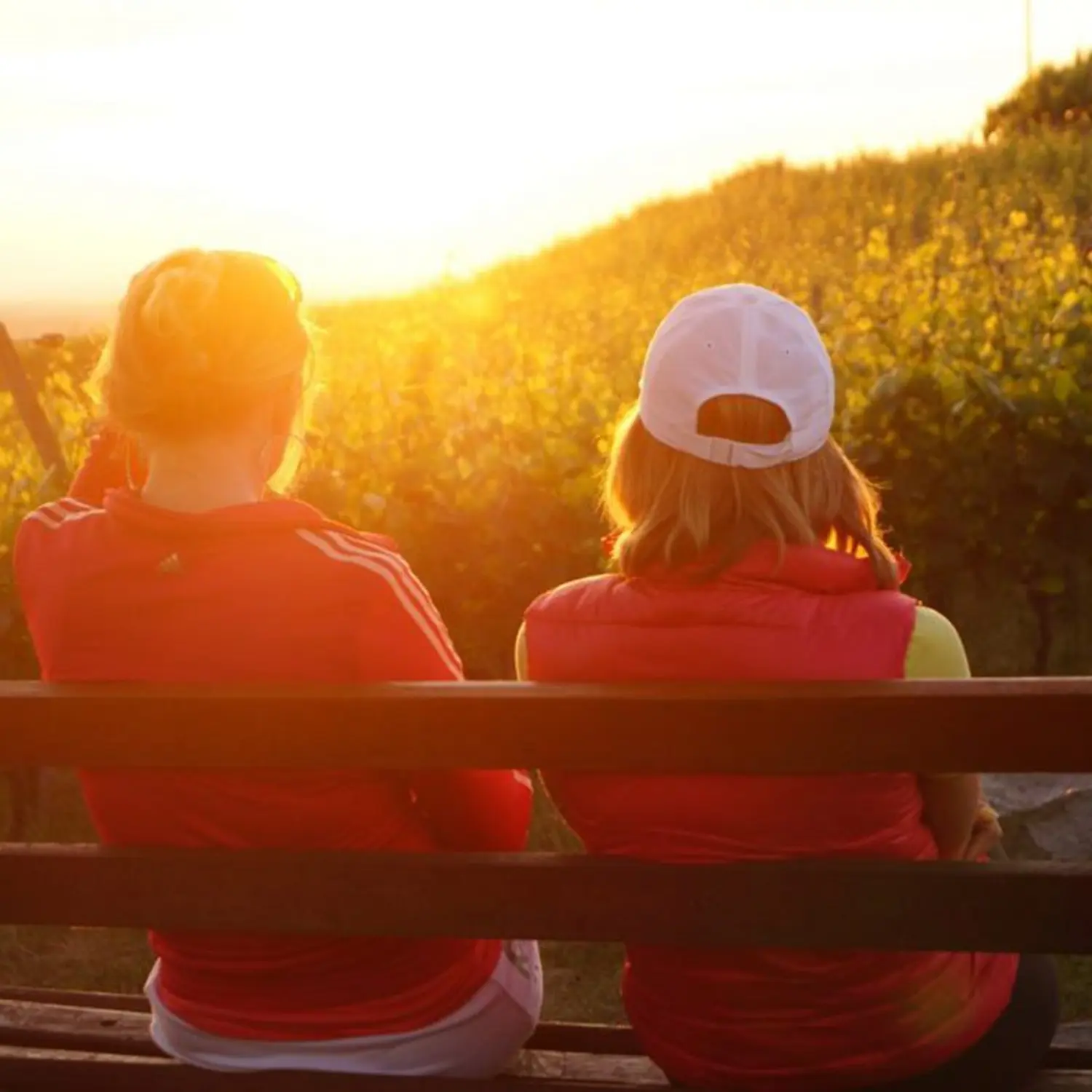 2 Mädchen sitzen auf einer Bank im Sonnenlicht