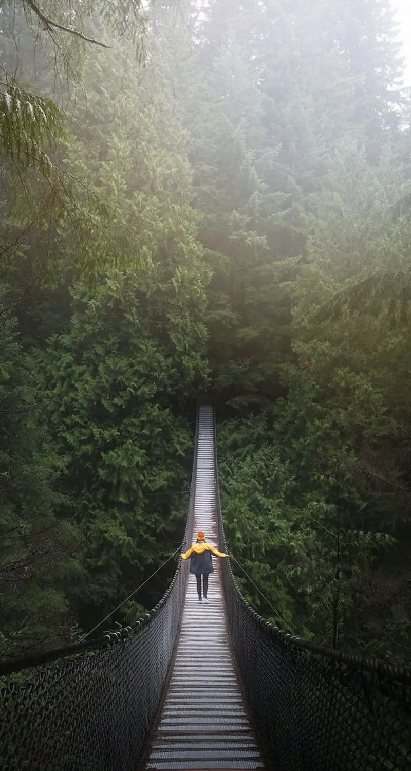 Eine Frau geht auf einer Holzbrücke im Wald